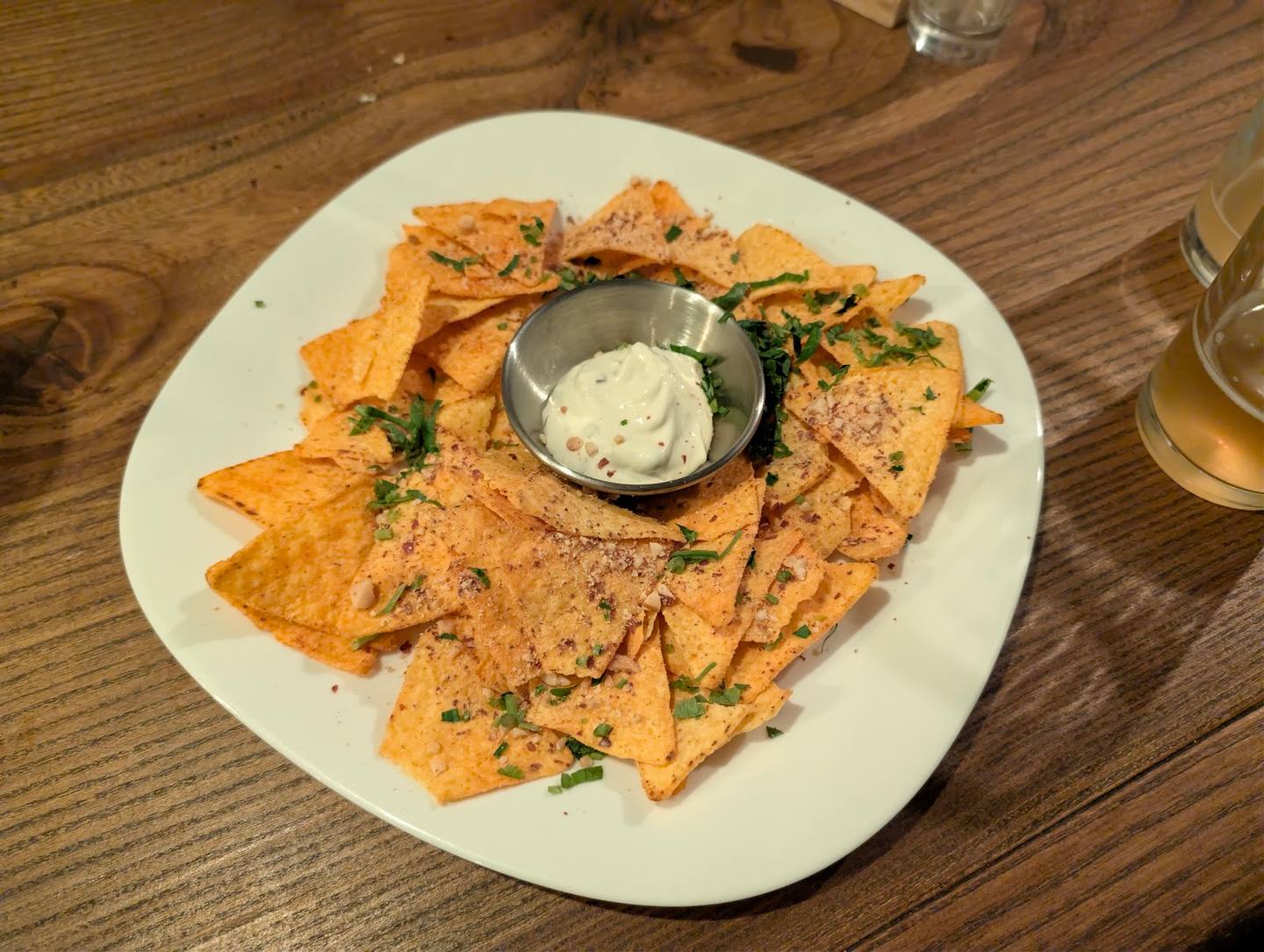 Crispy tortilla chips with herb seasoning and white dipping sauce