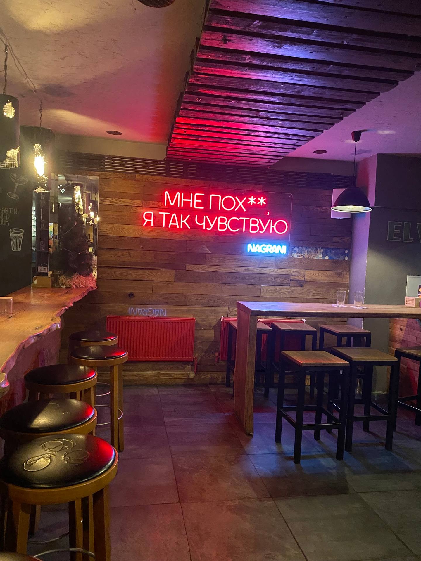 Modern bar interior with neon signage, colorful ambient lighting, and seating area