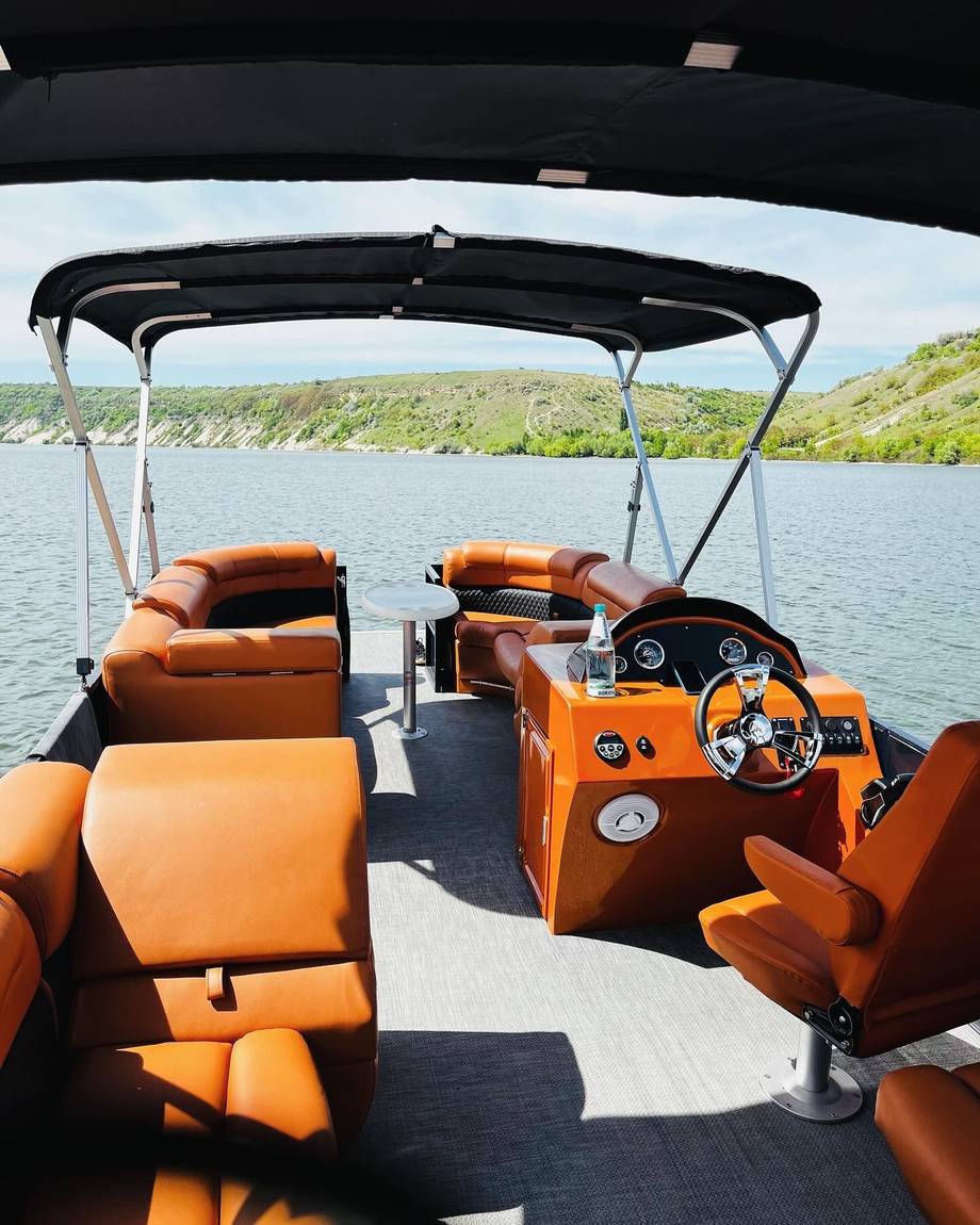 Orange speedboat interior with steering wheel and seating, lake view visible