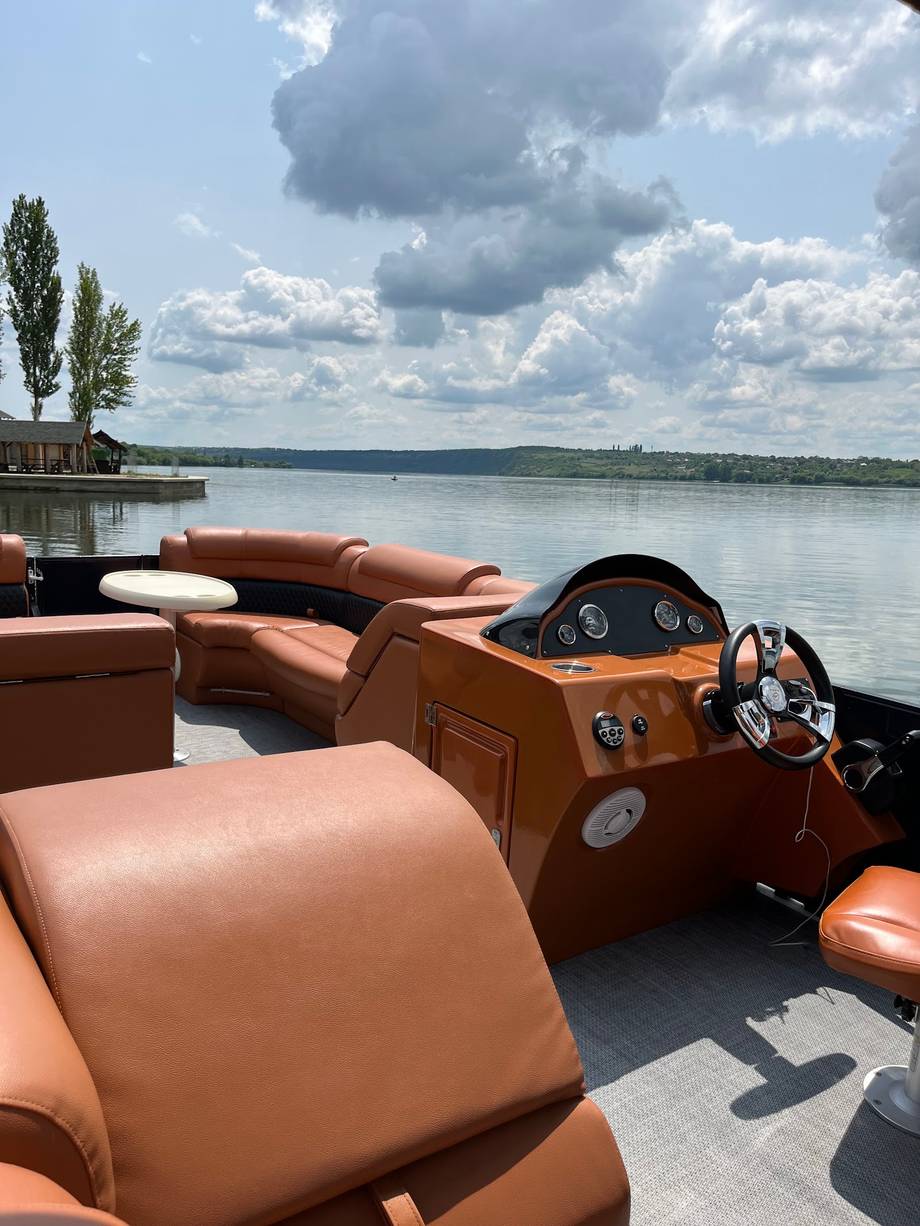 Luxury speedboat interior with tan leather seating and lake waterfront backdrop