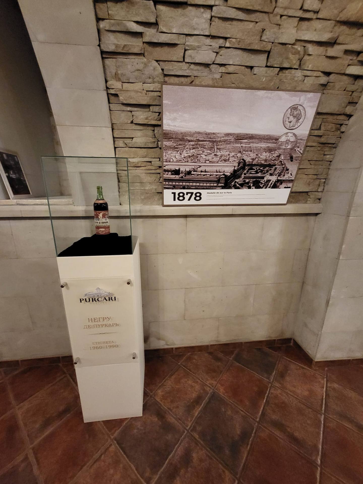 Wine bottle display with historical 1878 vineyard photograph on stone wall