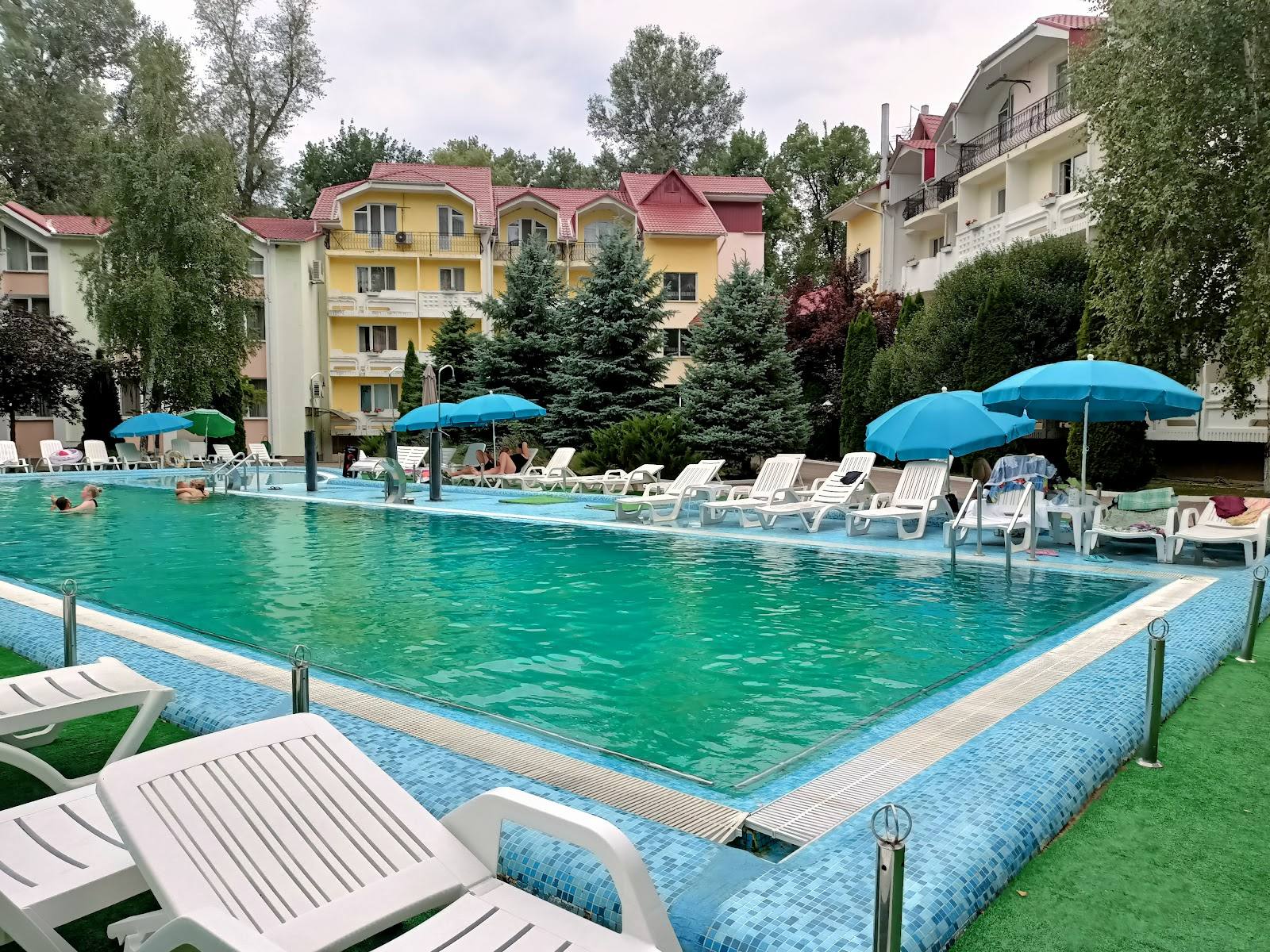 Resort swimming pool with terrace, loungers, umbrellas and residential buildings