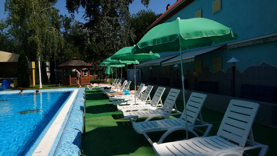 Pool area with loungers and green umbrellas at waterside venue
