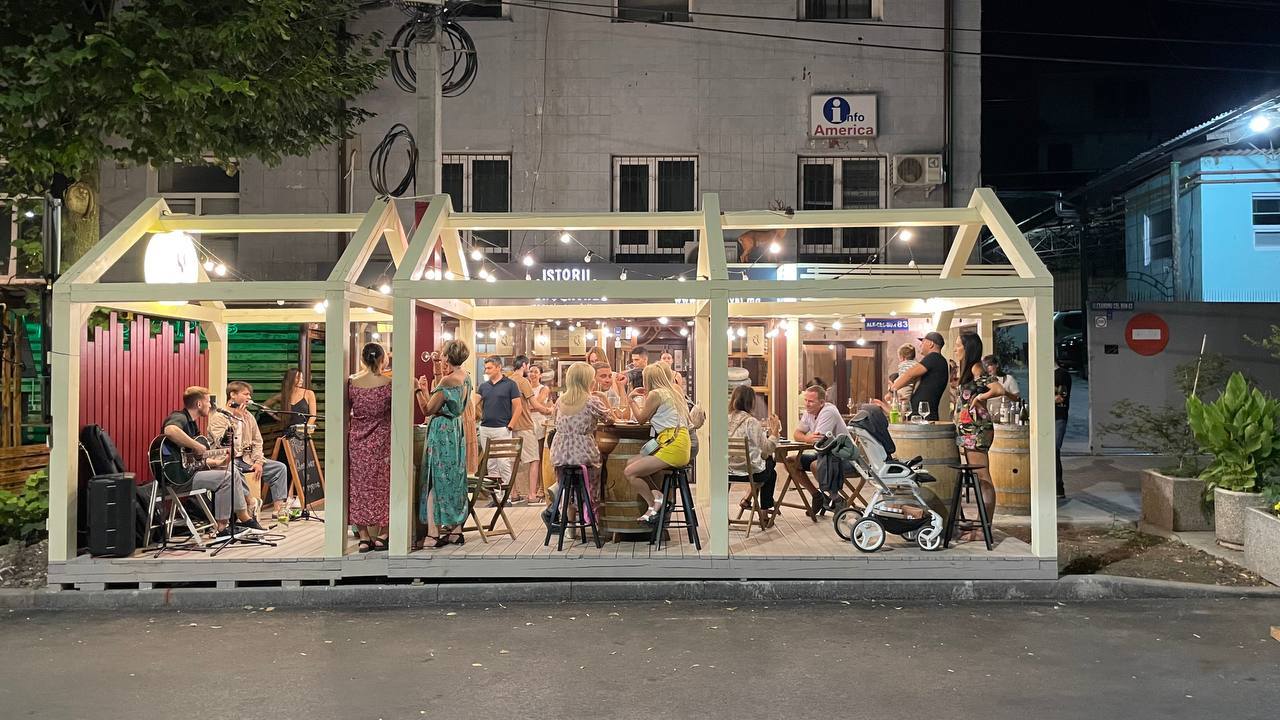 Illuminated storefront cafe with patrons dining and socializing at dusk