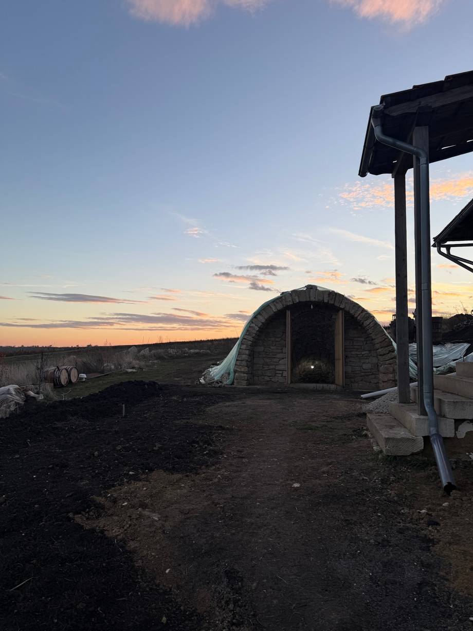 Wine cellar with arched stone structure at dusk, traditional barrel storage visible