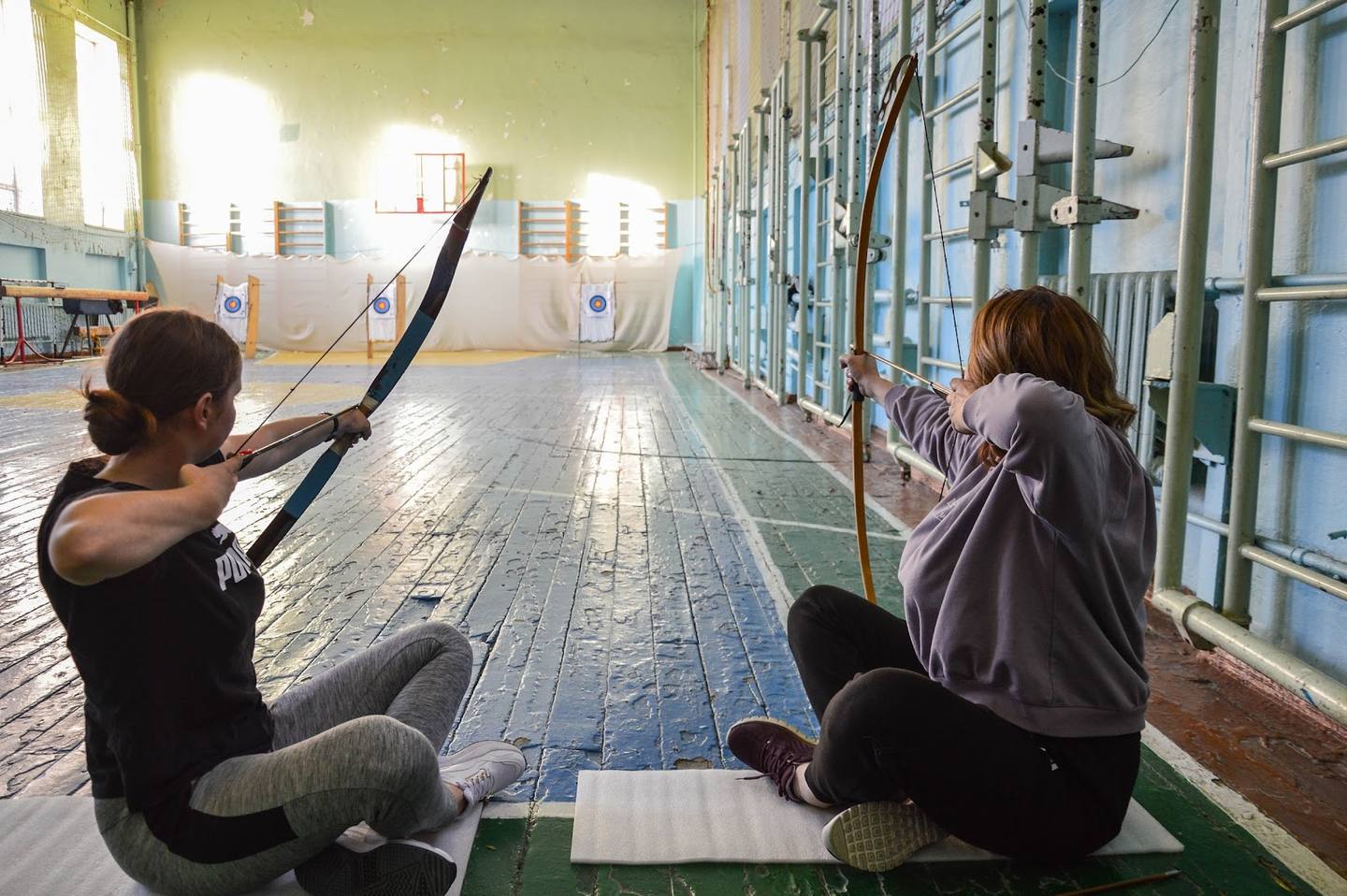 Archery activity room with participants practicing indoors under professional lighting