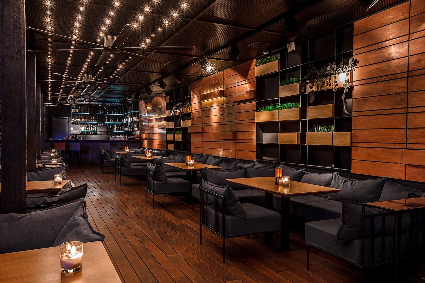 Modern lounge interior with warm wood paneling, ambient ceiling lights, and black seating