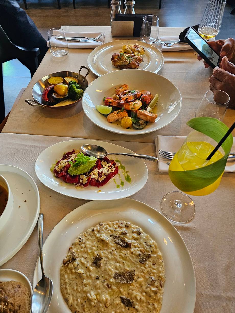 Fine dining plates with grilled shrimp, risotto, and seasonal vegetables on a wooden table