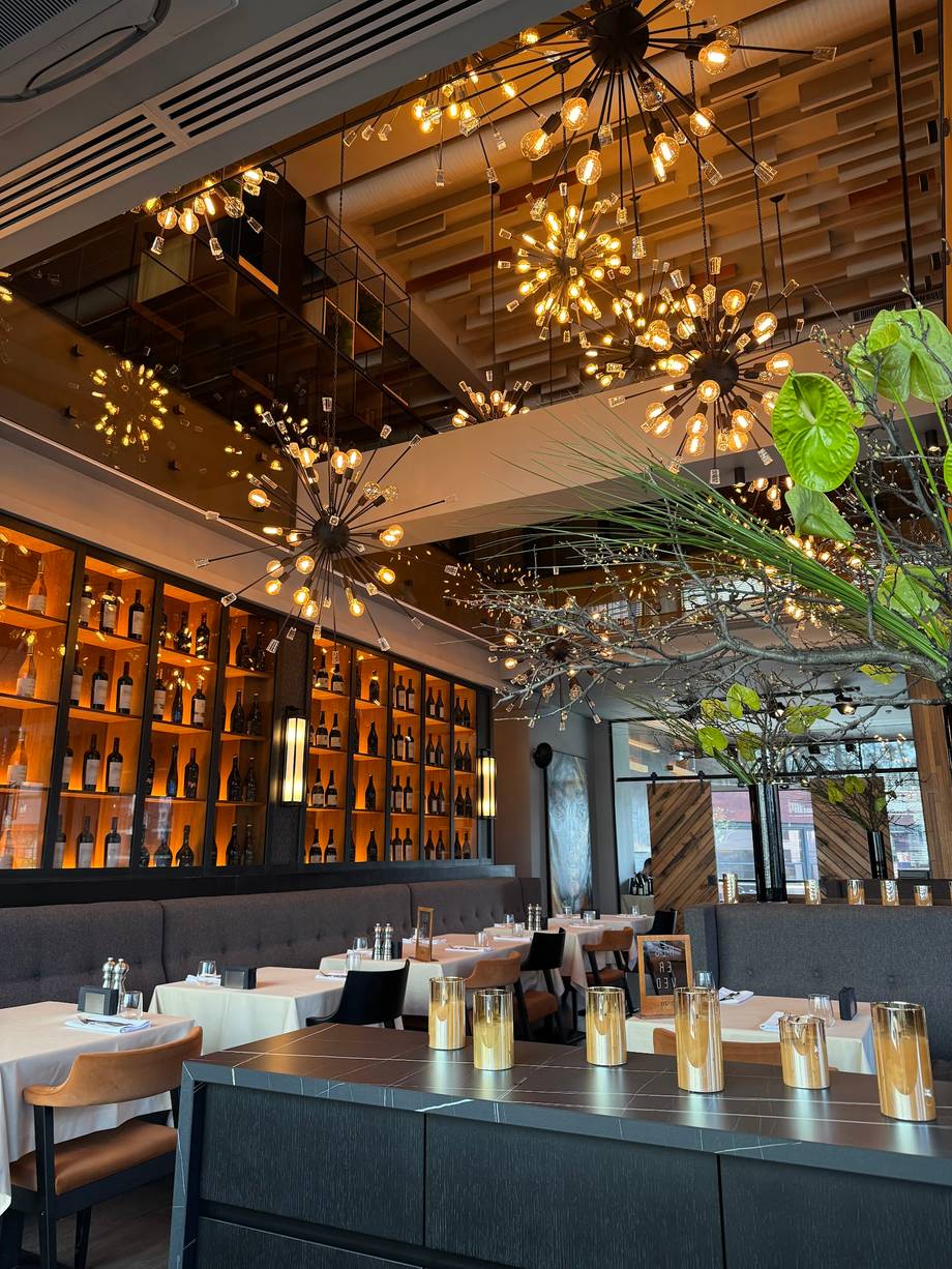 Modern restaurant interior with ambient lighting, bar counter, and wine display wall
