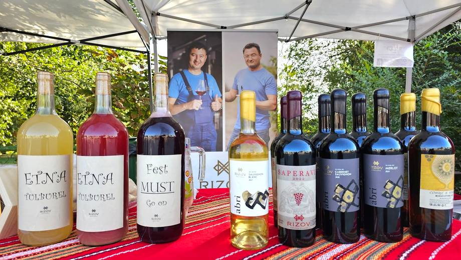 Wine bottles displayed at outdoor tasting event with vineyard owners under tent canopy