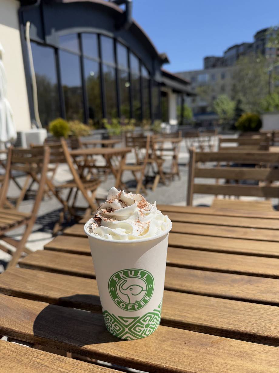 Signature whipped cream beverage on terrace with modern building and seating area
