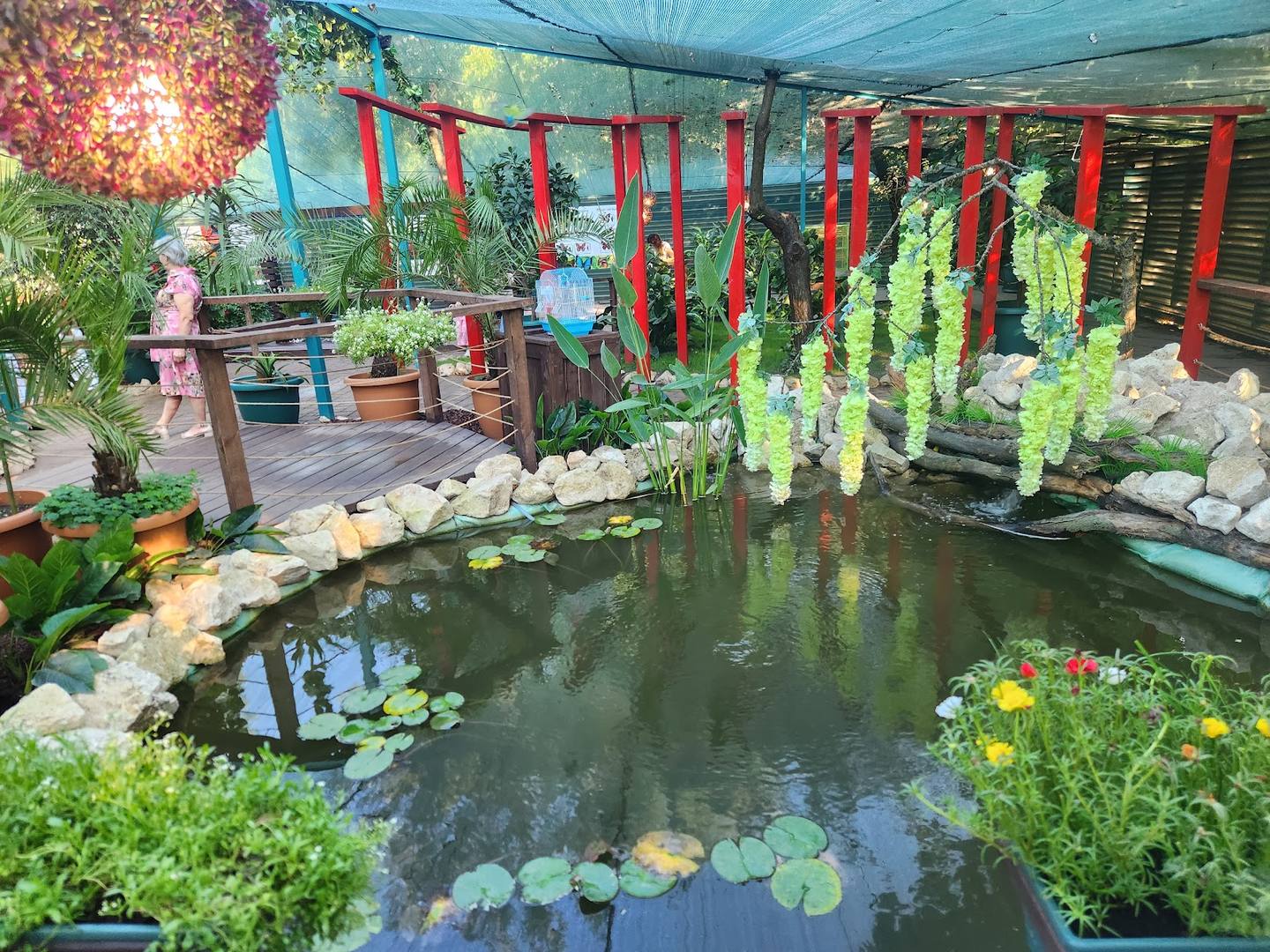 Indoor garden atrium with koi pond, hanging lanterns, and cascading green plants