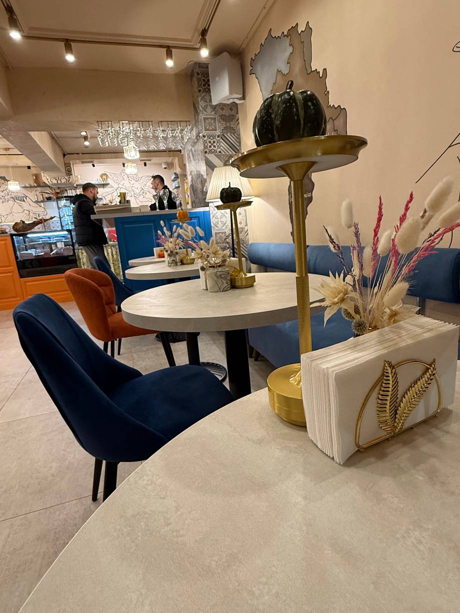 Modern cafe interior with blue velvet seating, white round table, and botanical decor