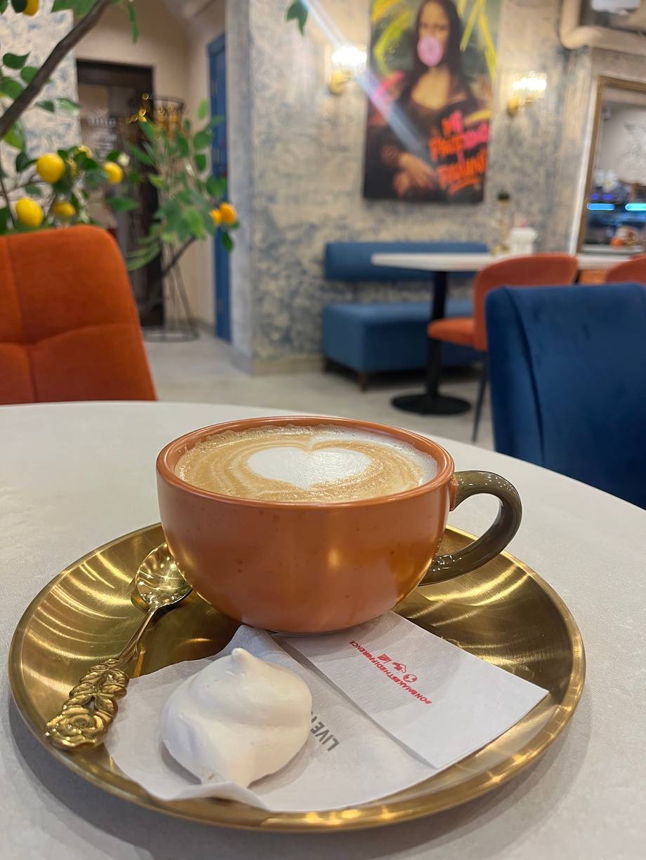 Artisan latte with latte art on decorative gold saucer in modern cafe interior