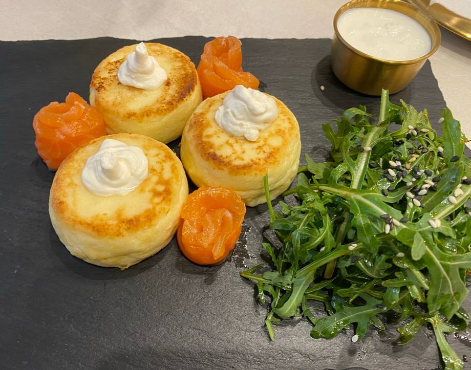 Gourmet appetizer platter with three pastries, sour cream, apricots, and microgreens
