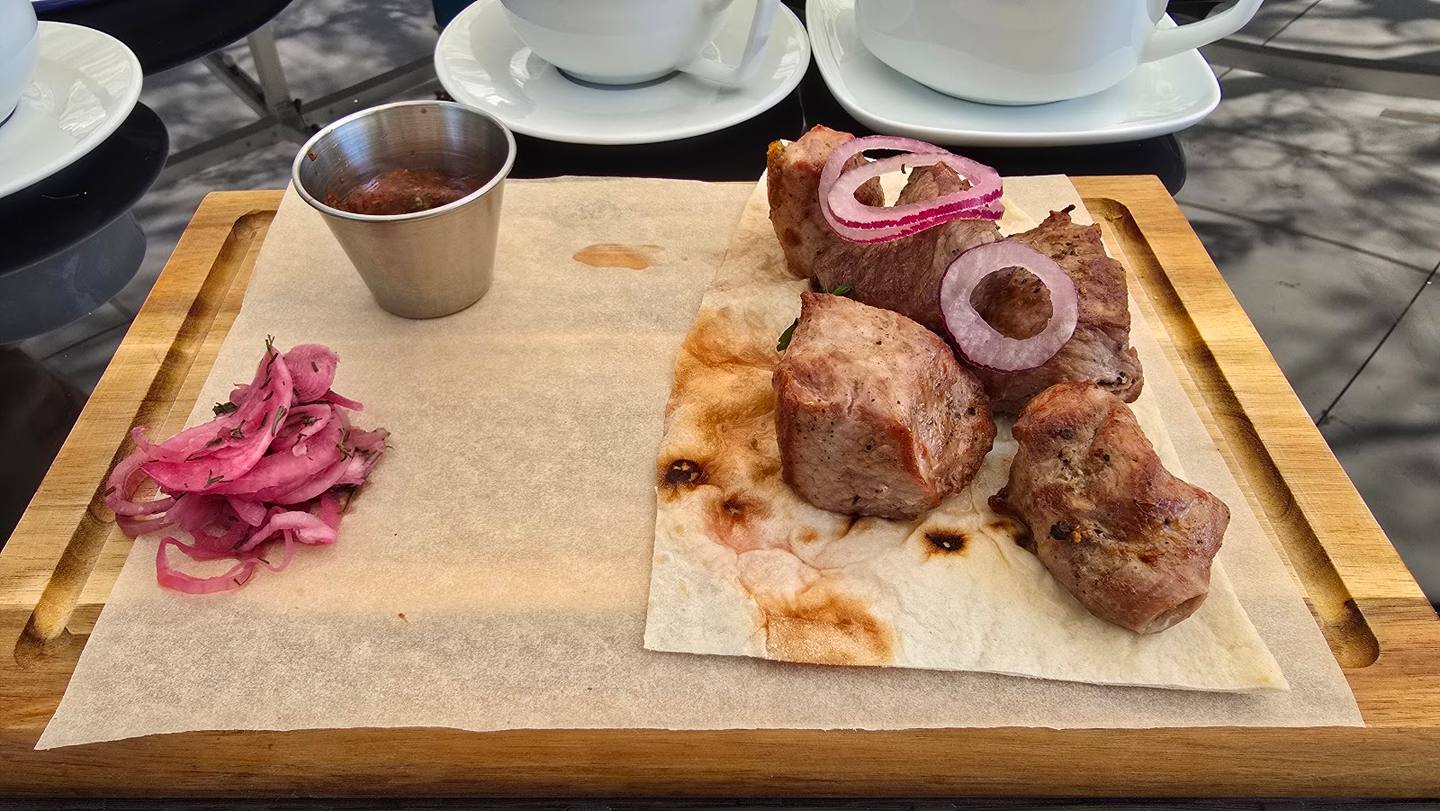 Plated charcuterie board with cured meats, pickled onions, and dipping sauce