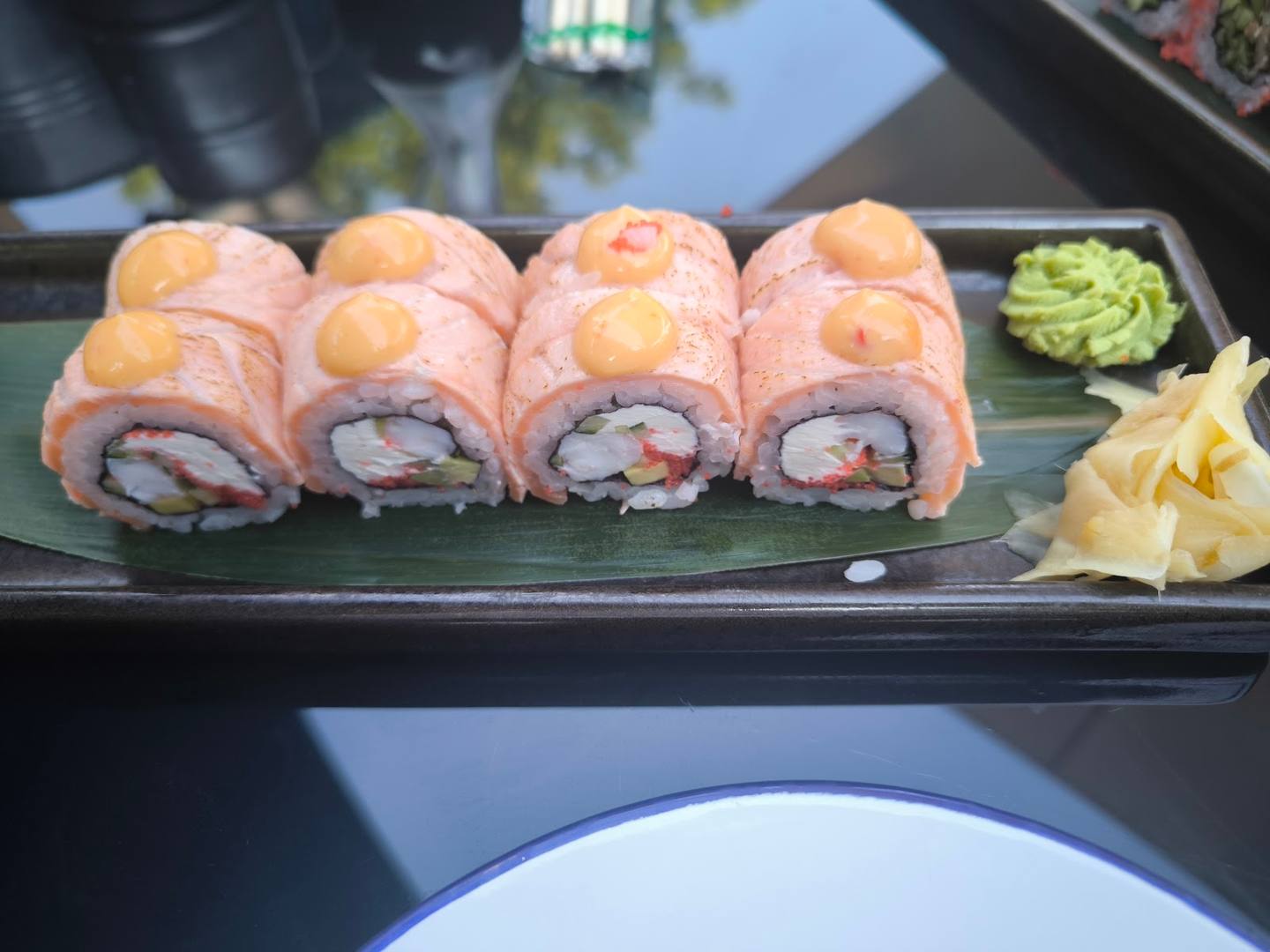 Sushi rolls plated on black dish with wasabi and ginger