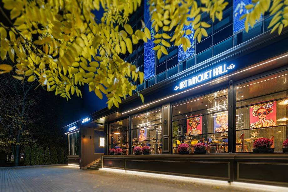 Illuminated storefront facade with signage and window displays at dusk