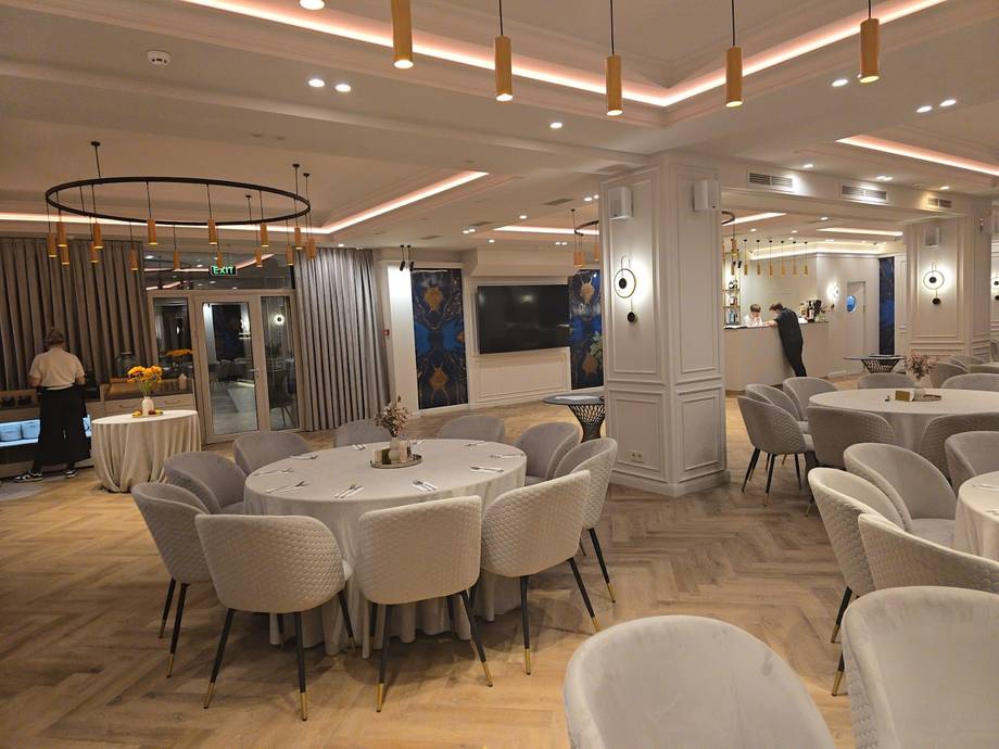 Modern event space with round dining tables, cream chairs, and contemporary ceiling lighting