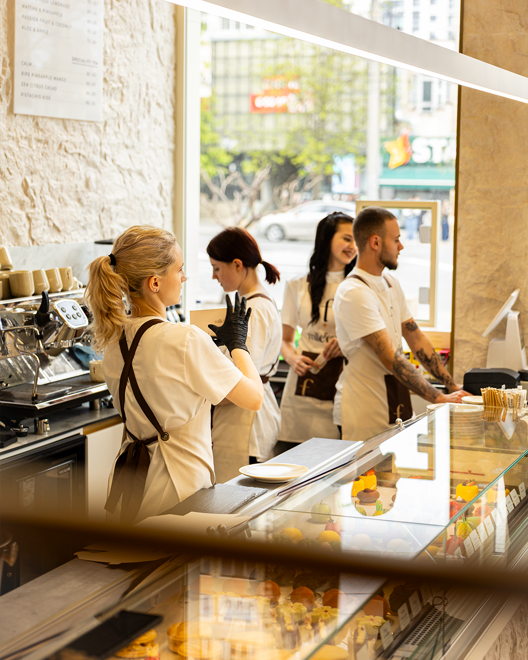 Coffee shop counter with barista team and street-side storefront windows