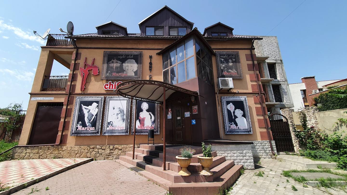Historic brick mansion with ornate facade, promotional posters, and manicured brick entrance approach