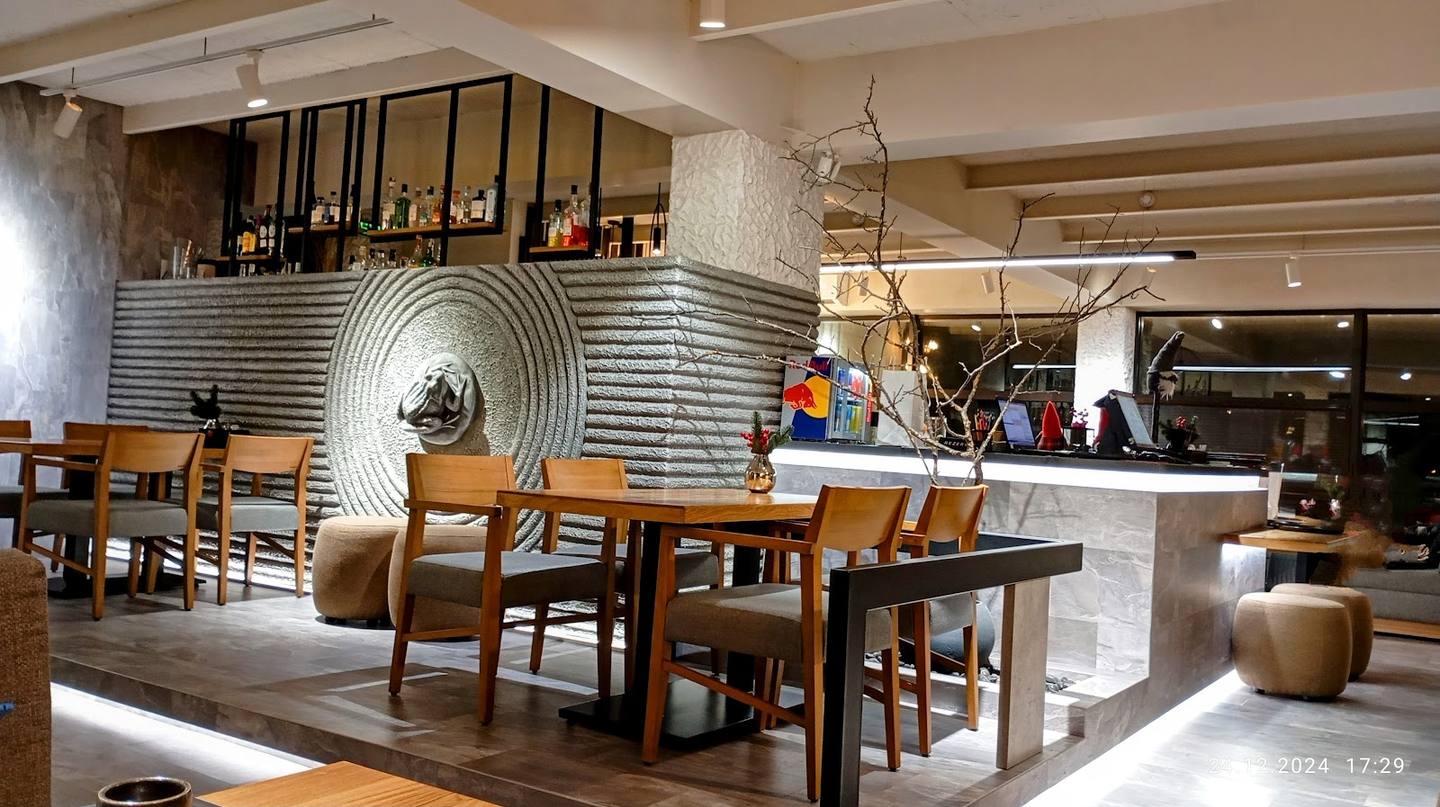 Modern dining and bar space with open kitchen, wooden furniture, and contemporary industrial design