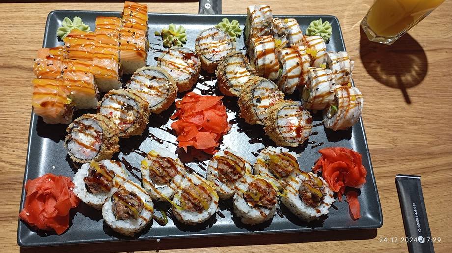 Sushi and grilled rolls platter with fresh garnish on slate presentation board