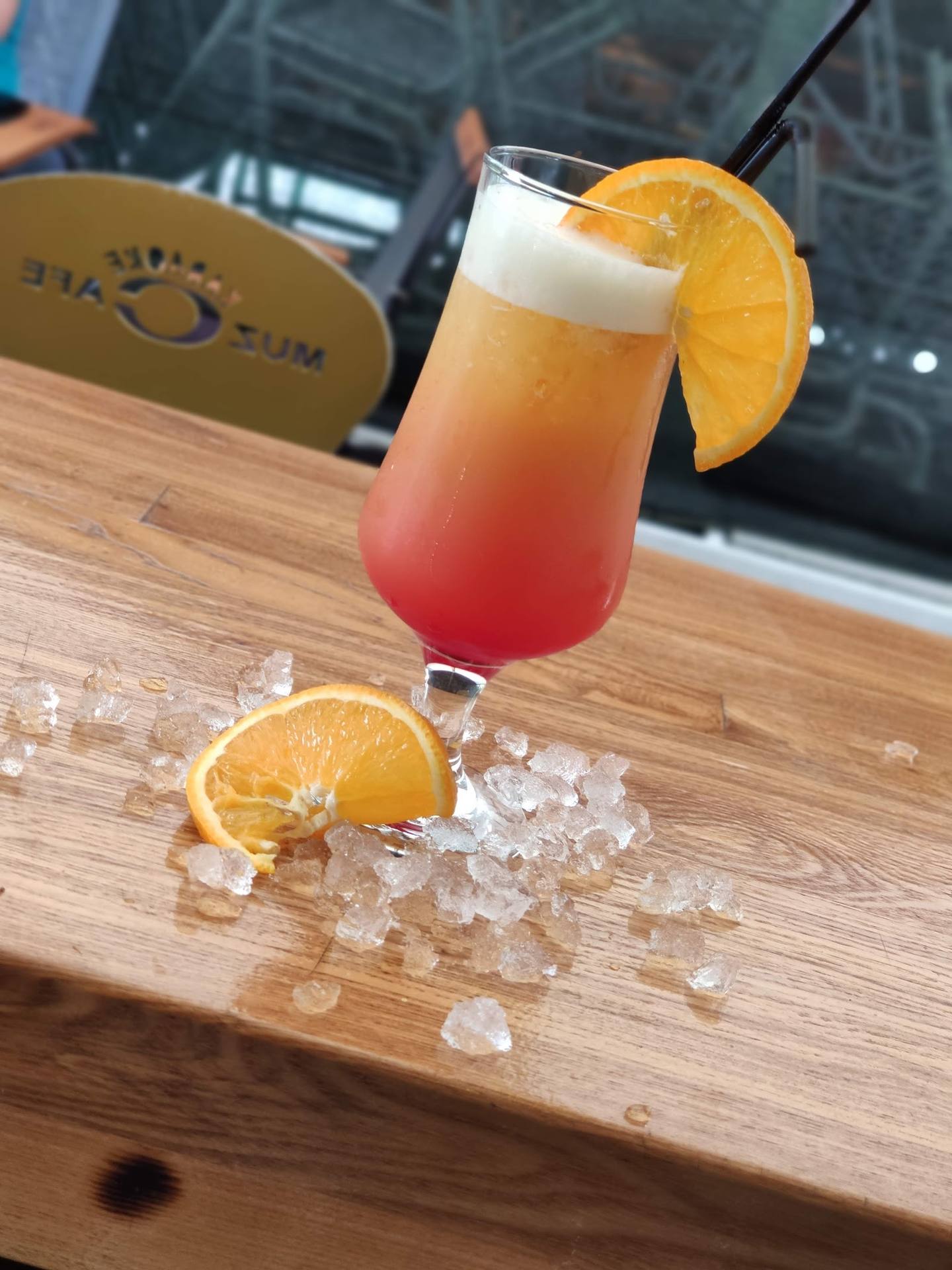 Craft cocktail with orange slice and ice on wooden bar counter