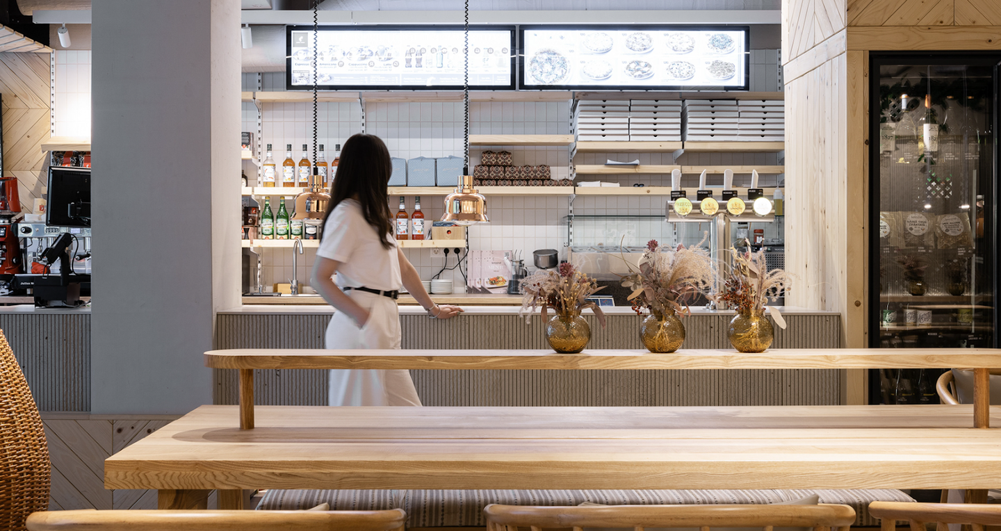 Modern cafe counter with barista and visible back-bar shelving and equipment