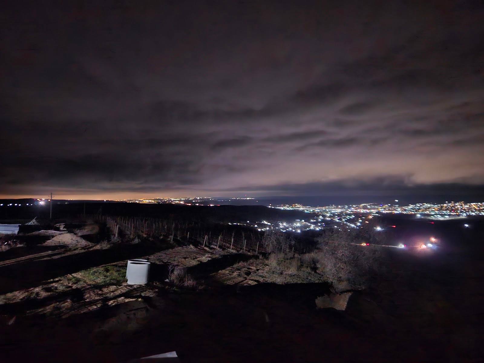 Fortress ruins at dusk with city lights visible in the distance below