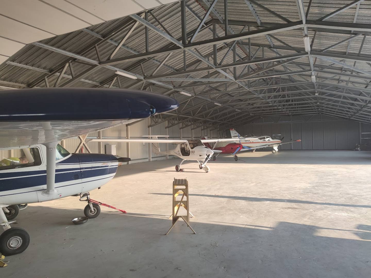 Aircraft hangar interior with multiple planes and industrial steel frame ceiling