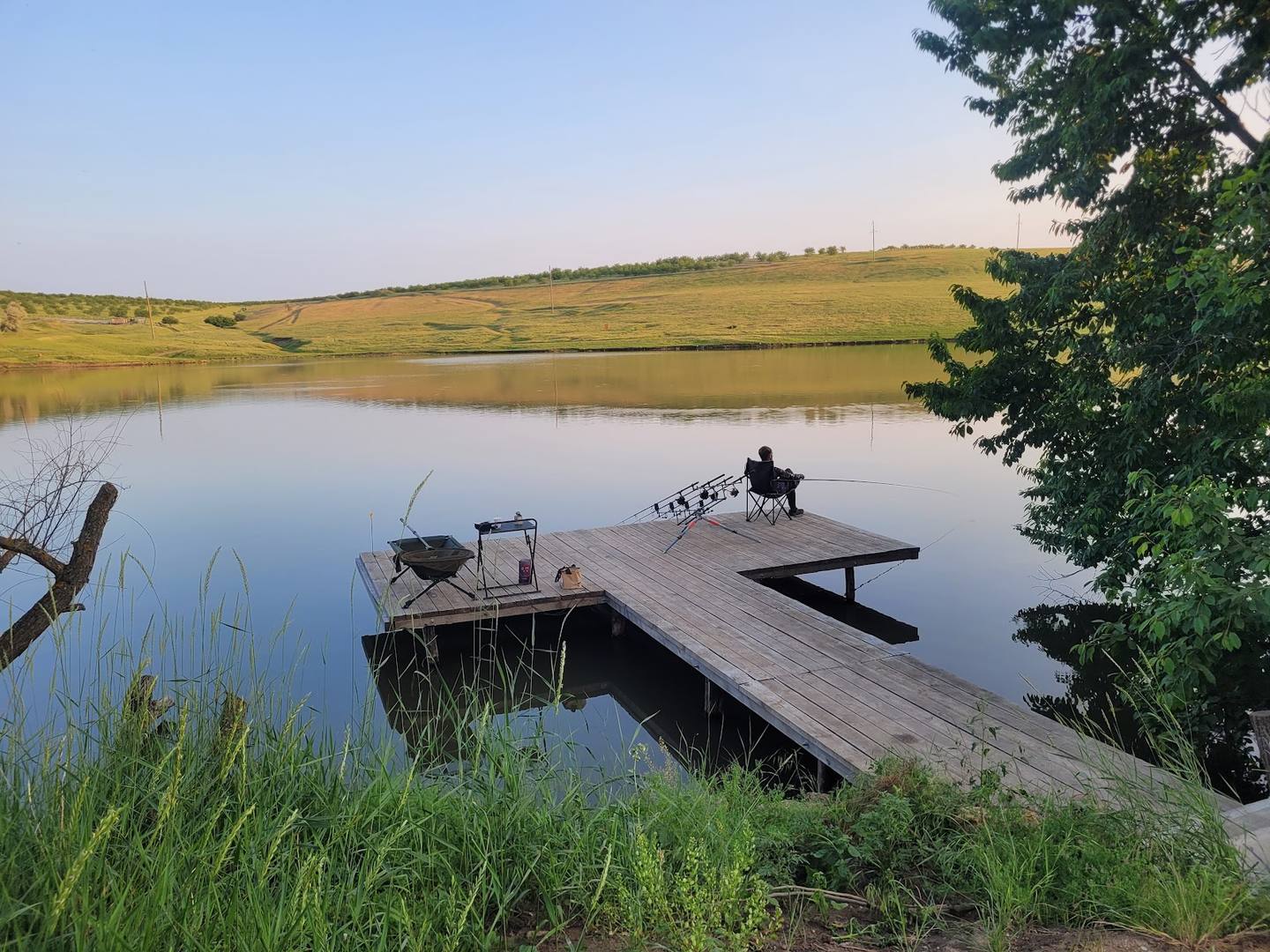 Wooden dock and boat on calm lake with pastoral countryside landscape