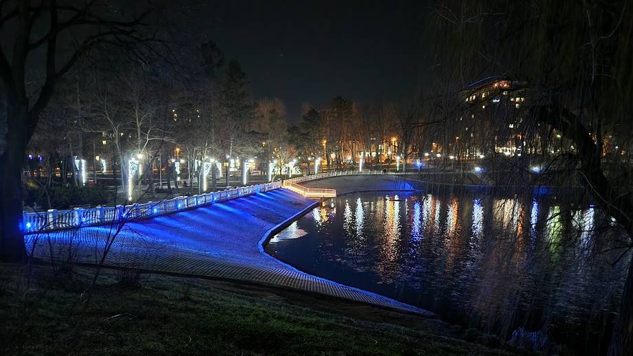 Illuminated riverside structure at night with urban architecture and water reflections