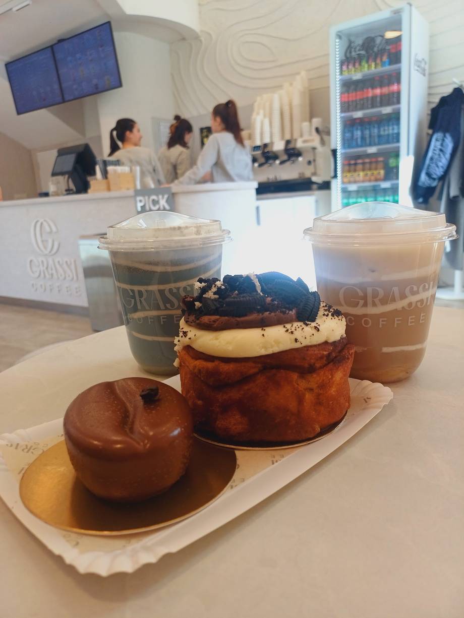 Pastry and coffee trio at modern cafe counter with beverage showcase