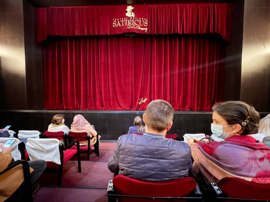 Theater interior with red curtains and audience seating during event