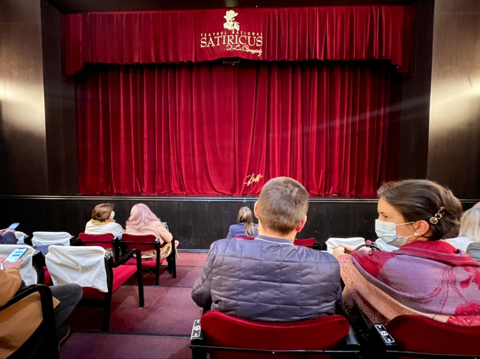 Theater interior with red curtains and audience seating during event