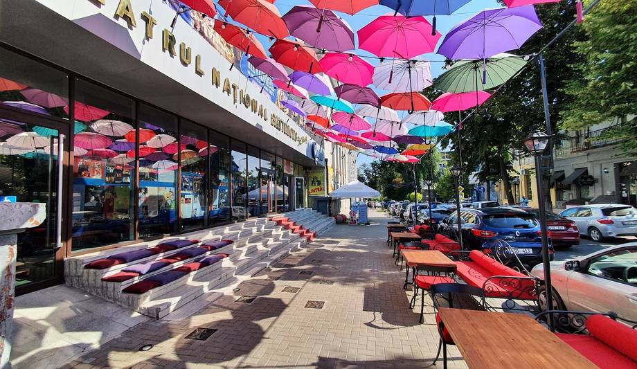 Vibrant outdoor terrace with colorful umbrella canopy and street-level seating