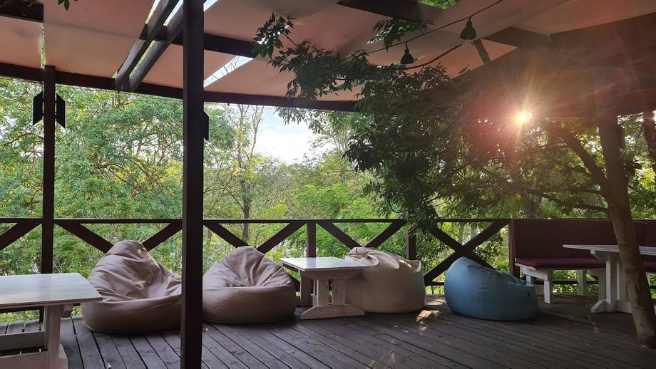 Open-air terrace with cushioned seating, rustic railings, and garden views