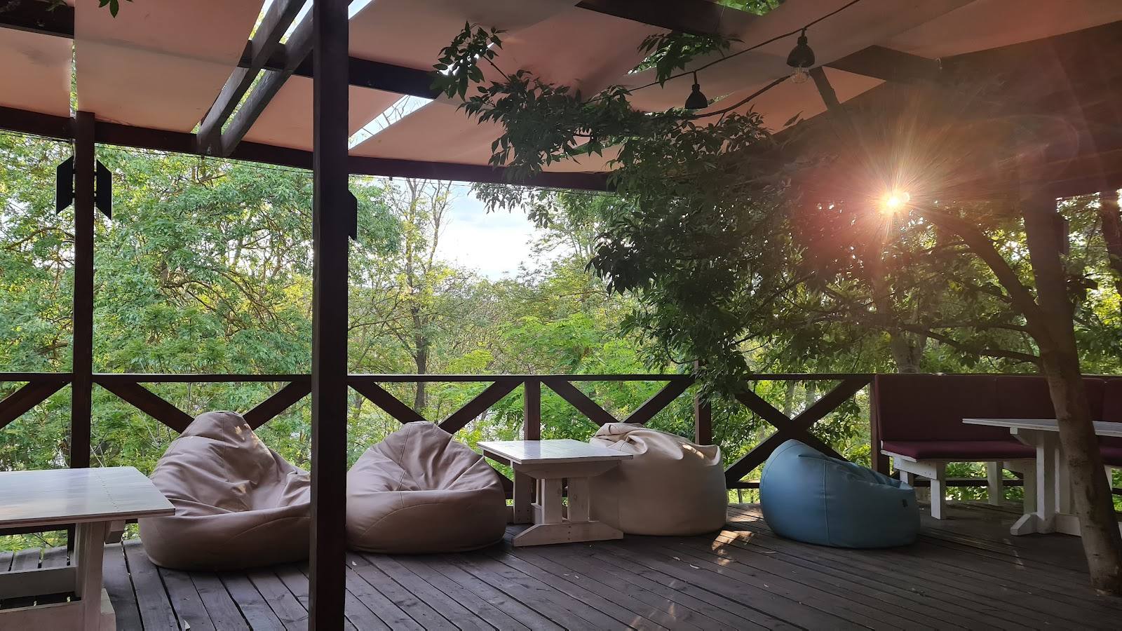 Open-air terrace with cushioned seating, rustic railings, and garden views