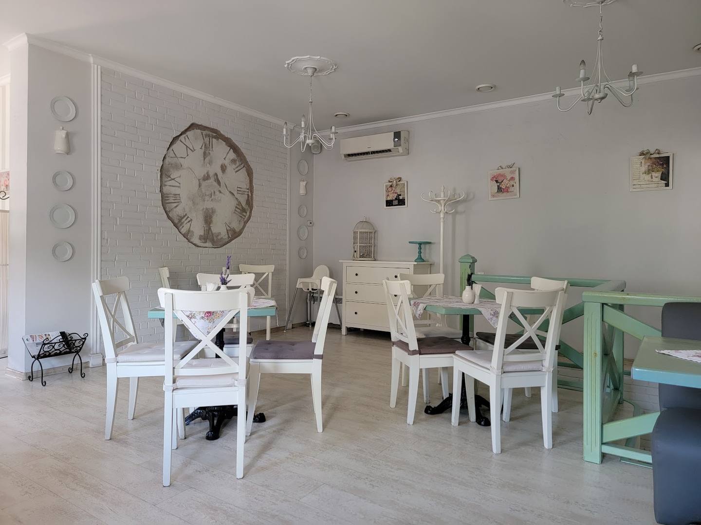 Bright café interior with white furniture, large clock, and mint-green accents