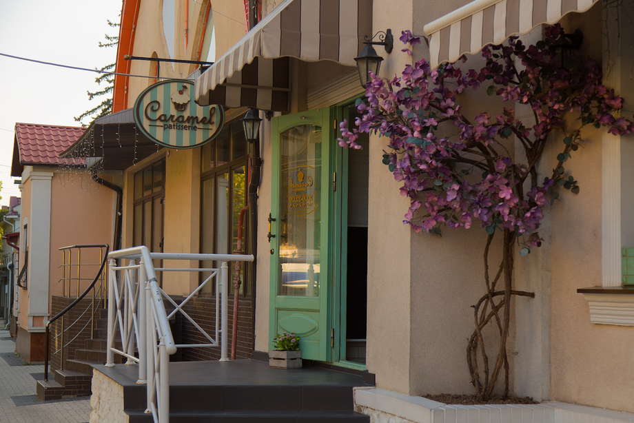 Charming storefront with green door, vintage signage, and purple flowering vines