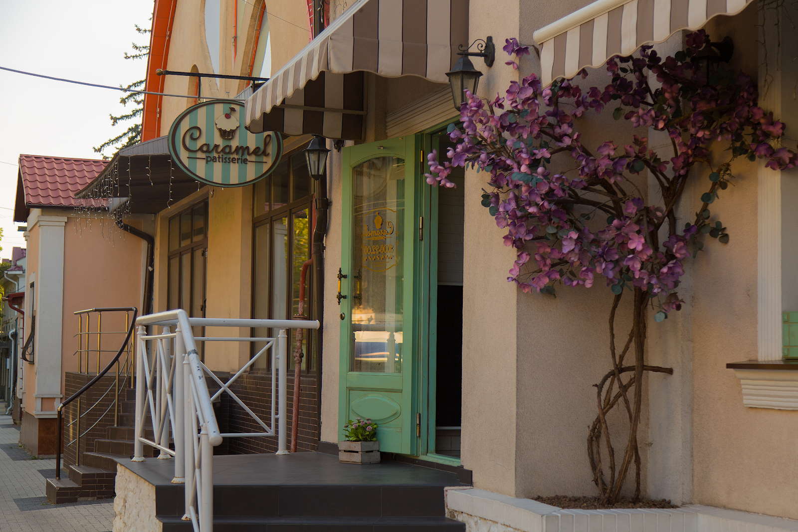 Charming storefront with green door, vintage signage, and purple flowering vines