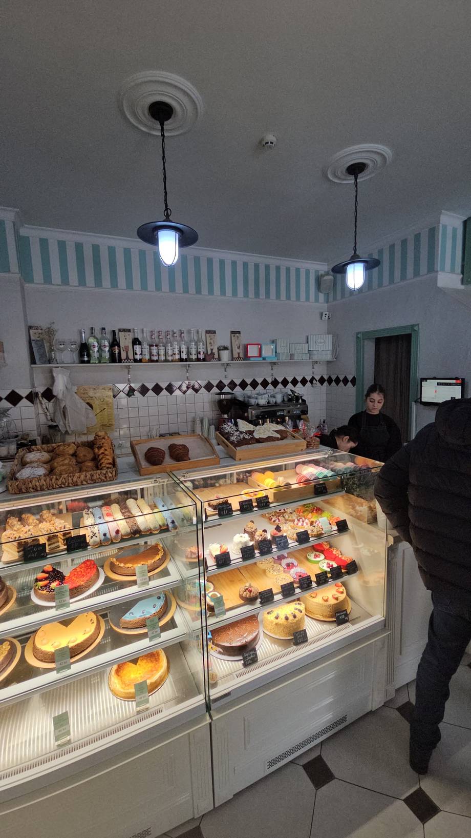 Bakery counter with display cases of pastries and cakes under pendant lights