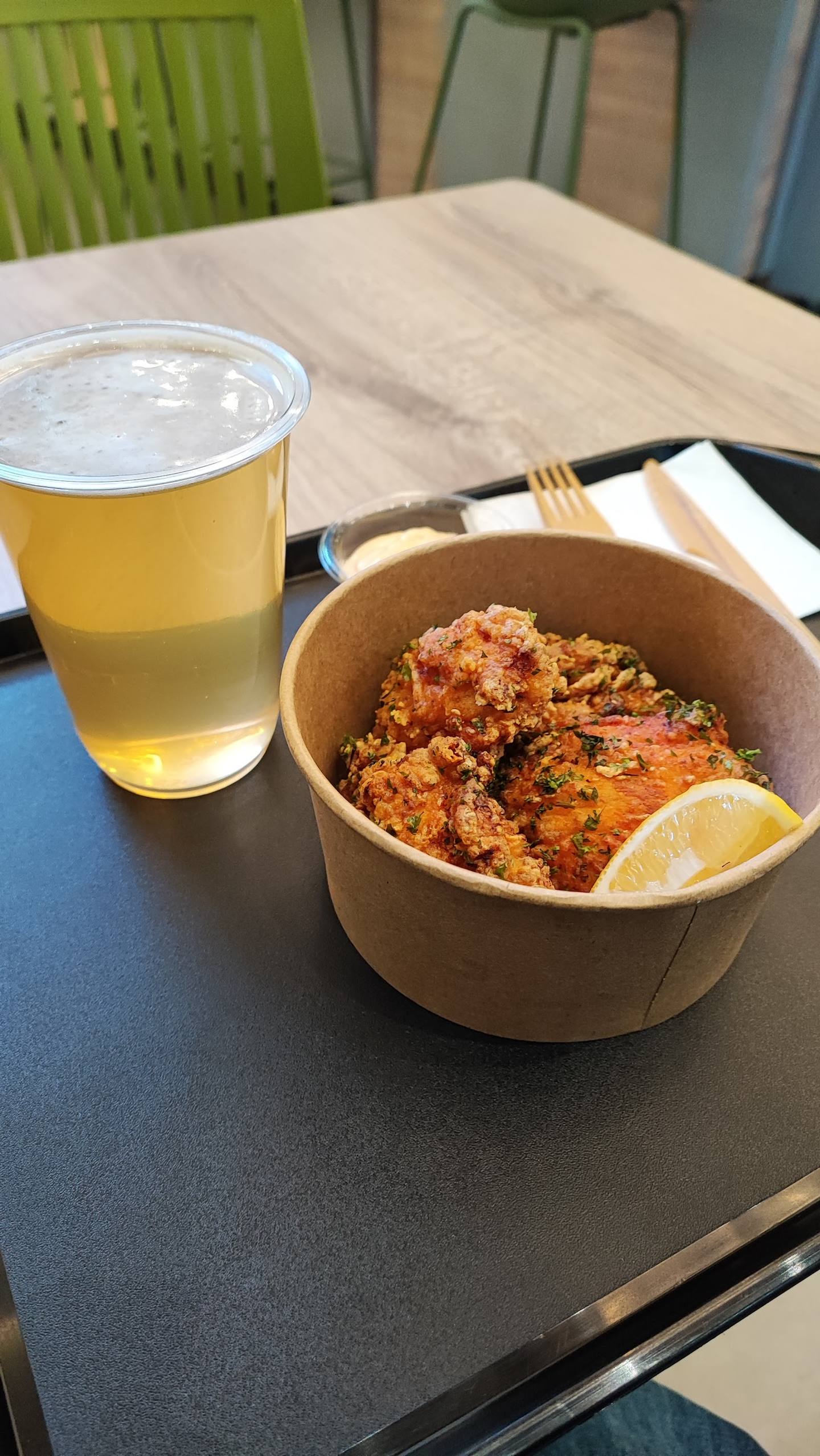 Craft beer and spiced chicken in paper bowl at casual dining venue