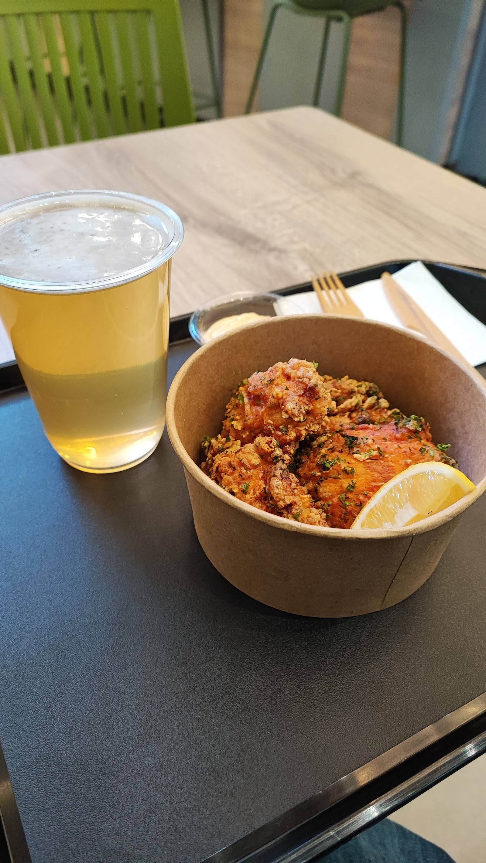 Craft beer and spiced chicken in paper bowl at casual dining venue