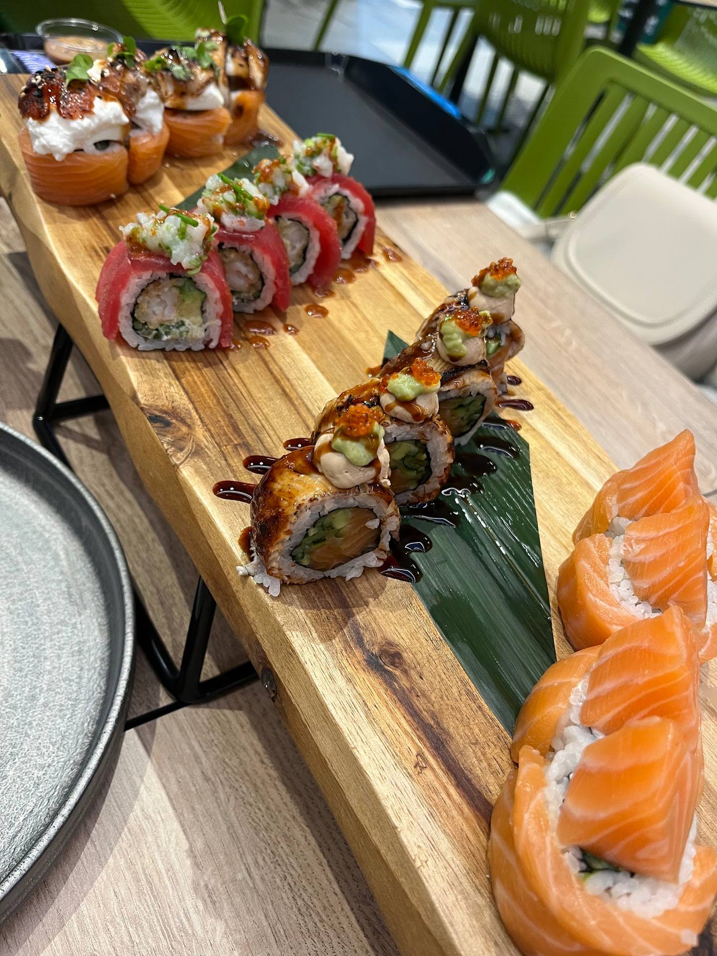 Assorted sushi rolls and nigiri on wooden serving board with fresh salmon