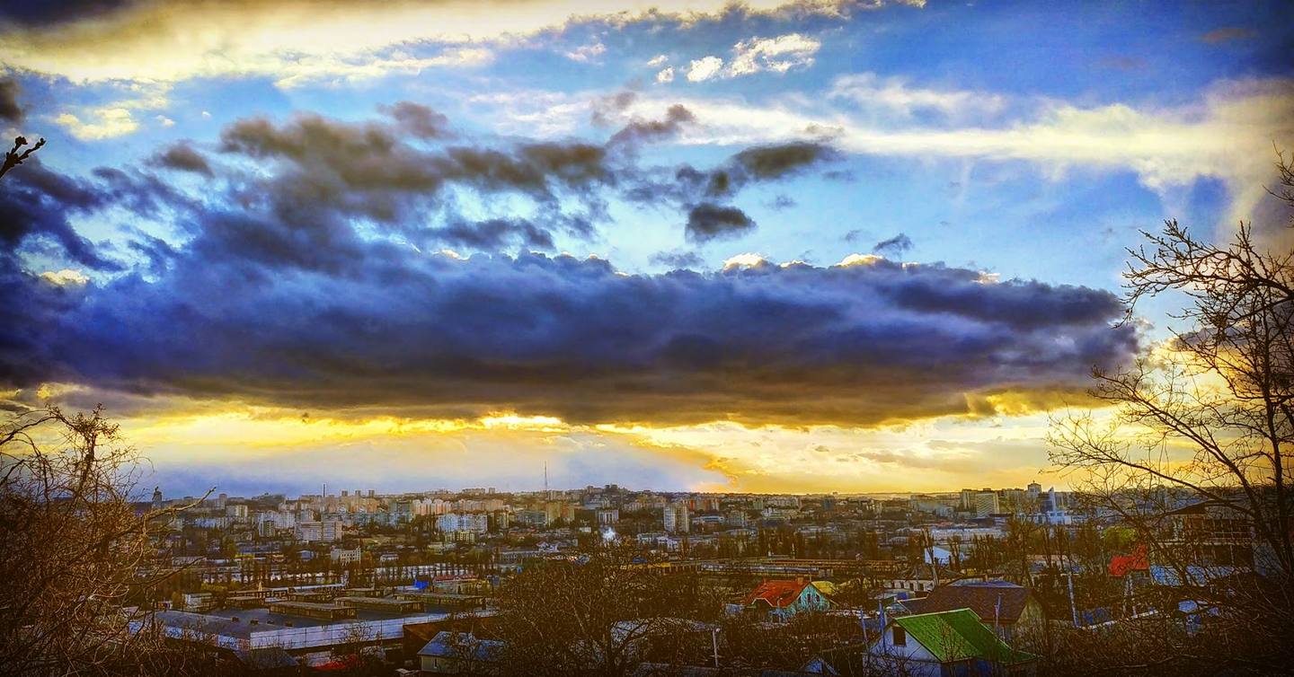 Sunset over cityscape with dramatic sky and scattered buildings