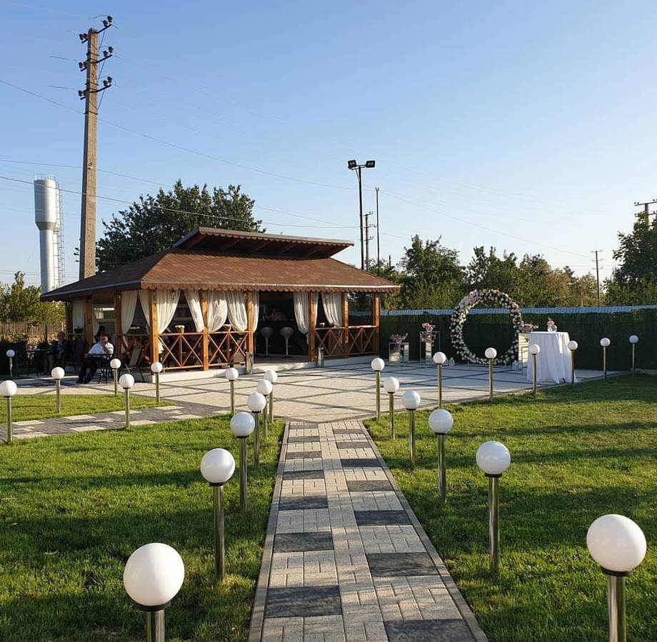 Modern wooden reception pavilion with manicured grounds and clear sky, Moldova event venue