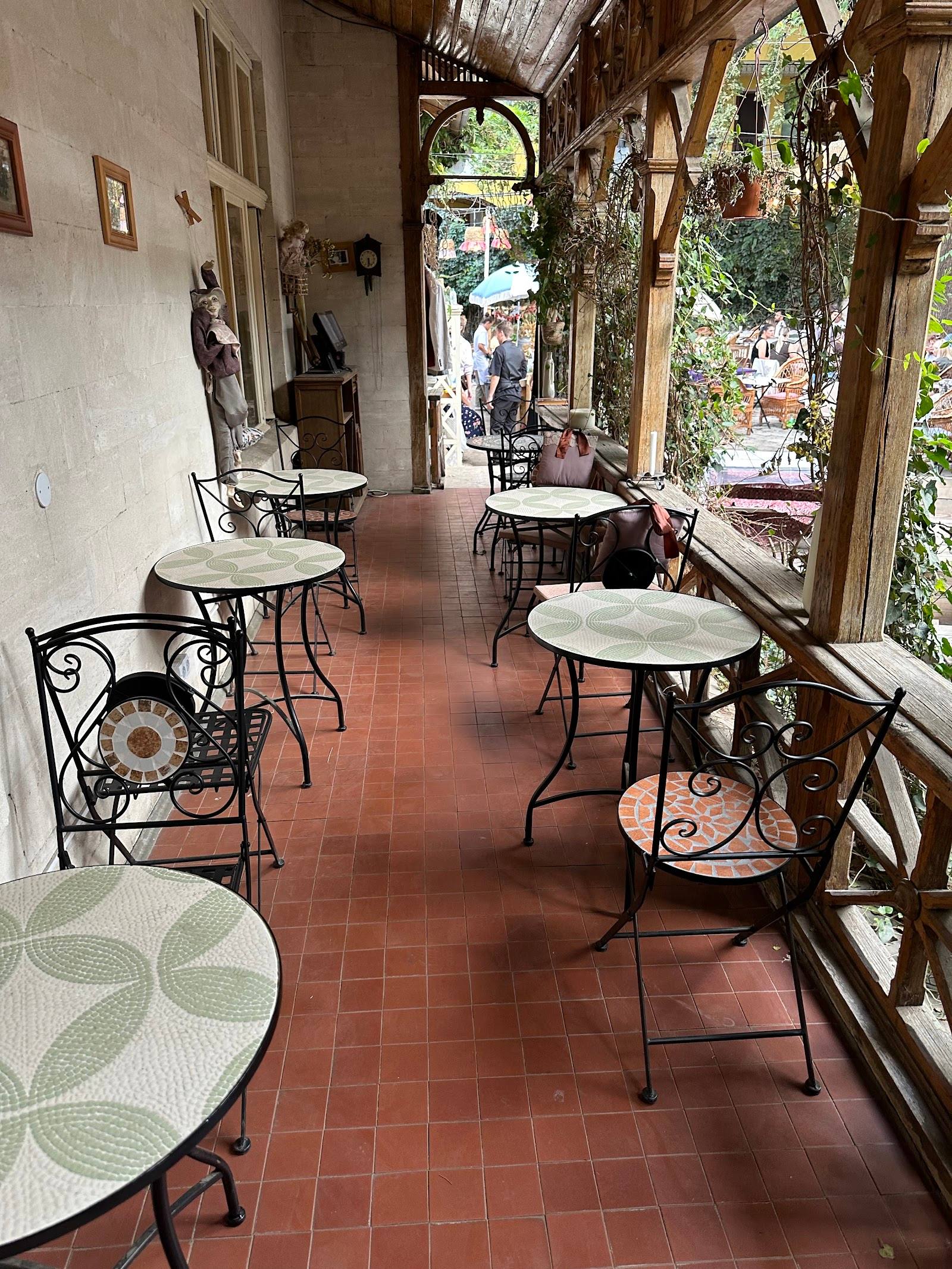 Covered terrace seating with arched doorways, vintage decor, and garden views at a traditional cafe