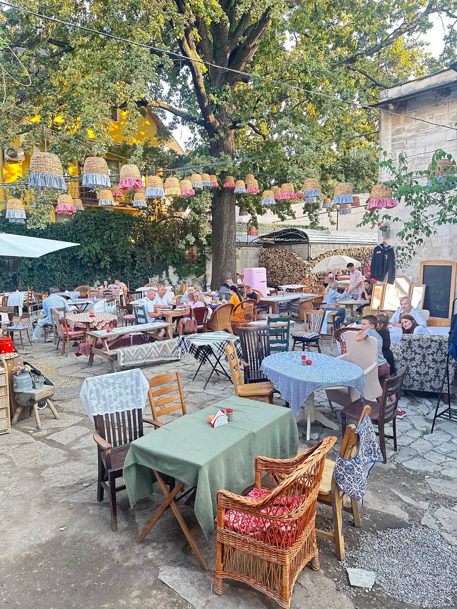 Outdoor garden terrace with rustic tables under mature tree and hanging florals